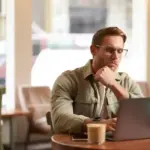 Person focusing work at desk laptop coffee