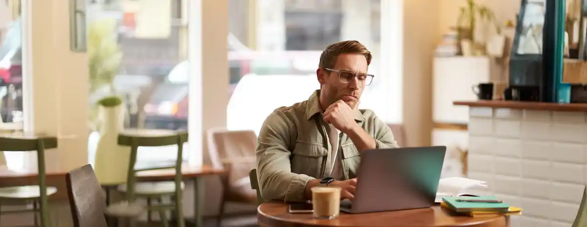 Person focusing work at desk laptop coffee
